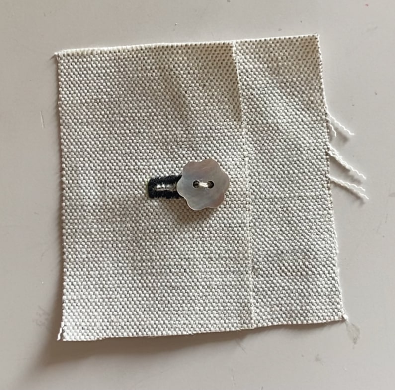 Le bouton est inséré dans la boutonnière et les bords du coupon sont alignés.