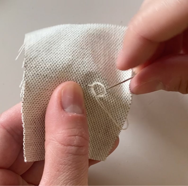 Une couturière réalise un point d'arrêt à l'arrière du tissu.