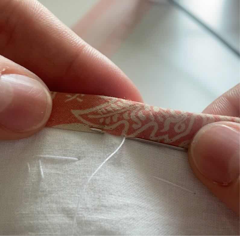Une couturière fait sortir l'aiguille à 5mm de sa dernière piqure et en profite pour piquer dans le biais à ce moment là.