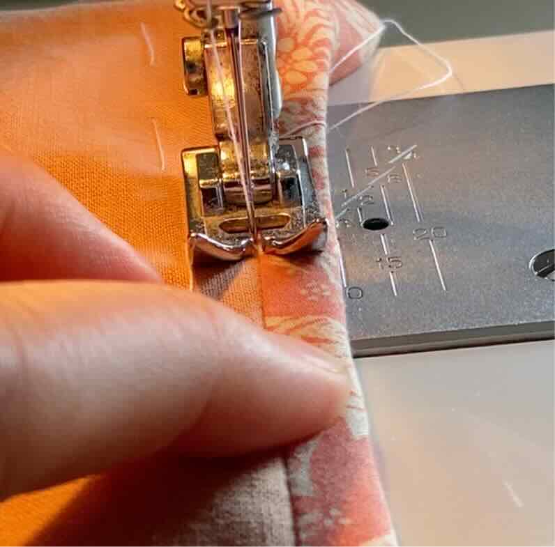 L'aiguille de la machine longe le biais sur l'endroit du tissu pour coudre le biais.